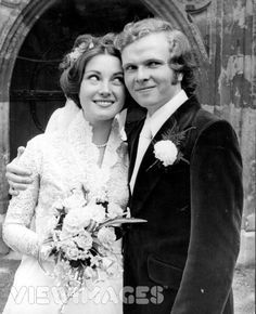 a bride and groom posing for a photo in front of an old church door with flowers on the bouquet