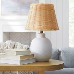 a white vase sitting on top of a wooden table next to a lamp and books