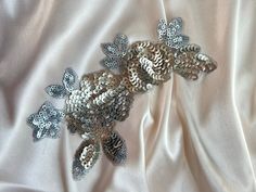 silver sequins and pinecones on white satin