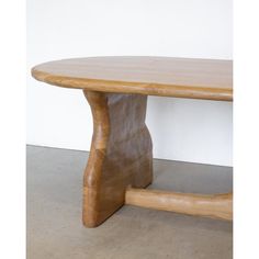 a wooden table sitting on top of a cement floor next to a white wall in a room