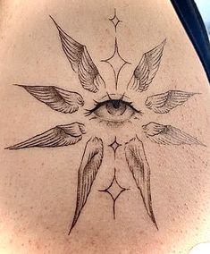 the back of a woman's stomach with an eye and wings tattoo on it