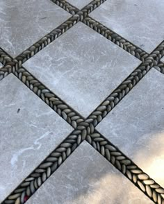 a close up view of a tile floor that has braided edges and red flowers on it