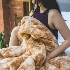 a woman sitting on a bed covered in a teddy bear blanket