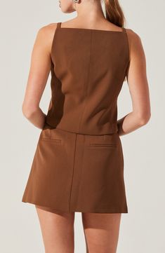 the back view of a woman wearing a short brown dress with pockets on one side