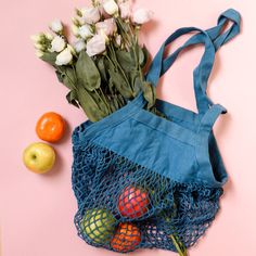 a blue bag sitting next to some fruit and flowers