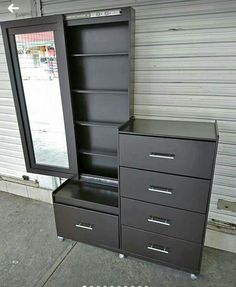 a dresser with a mirror and drawers in front of a garage door