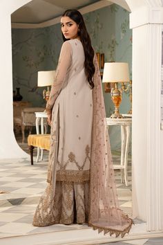 Ivory Embroidered Pakistani Wedding Dress in Kameez Sharara Style is a stunning attire with the perfect balance of royalty and elegance. Kora, Dabka, Gotta, and Zardosi give a glamorous touch to this perfectly stitched Sharara Dress, making it an epitome of beauty and grace. Embroidered Kameez: The kameez comes in premium Chiffon fabric. Hand-crafted details of Kora Dabka, Zardosi, Swarovski, Sitara, and gotta give a traditional look to this organza kameez. Embellished work on the kameez gives a perfect finish to the stunning kameez. Sharara Kameez: The embellished kameez Dress is paired with Sharara to create a ravishing Pakistani Wedding Dress. The Sharara has a huge flare and is emblazoned with elegant designs. Organza Dupatta: Pakistani Wedding Dress in Sharara Kameez style achieves th Suit Designs For Wedding, Gold Salwar Kameez, Sharara Style, Red Dupatta, Zardosi Embroidery, Pakistani Wedding Dress, Chiffon Collection, Organza Dress, Wedding Function