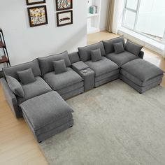 a living room with a large gray sectional couch in the center and pictures on the wall