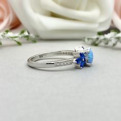 This beautiful ring is made from genuine 925 sterling silver with rhodium plating. Ring details- -The Main stone is a round cut 6mm Lab Created Light Blue Opal Stone -Side stones are 4mm by 2mm Lab Blue Sapphire Marquise and 1mm Round simulated diamonds -Ring is casted in solid 925 sterling silver with rhodium plating (yellow gold and rose gold plated also available, please check the drop down menu for more options) -The Total face height of the ring measures 7mms and the band width measures 1.5 Blue Opal Birthstone Ring In Sterling Silver, Blue Cubic Zirconia Round Band Jewelry, Blue Topaz Three Stone Blue Jewelry, Elegant Blue Opal Promise Ring, Blue Sterling Silver Rings With Accent Stones, Blue Three Stone Sapphire Ring In Sterling Silver, Blue Cluster Ring Gift Round Cut, Blue Oval Birthstone Ring In Sterling Silver, Blue Oval Sterling Silver Birthstone Ring