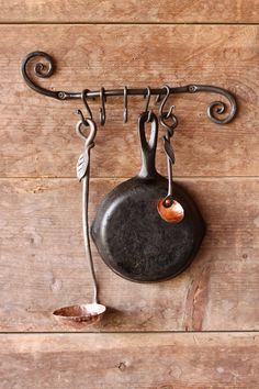 an old frying pan hanging on a wall with a metal hook attached to it