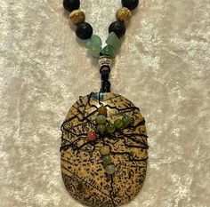 Dendritic Picture Jasper cabochon wrapped in black wire with India and Moss Agate added to the wrap. The cabochon is 2 1/8" long and 1 1/2" wide. Huge!  A mix of Aventurine, Black Lava, Carnelian and Silver alloy beads on 1mm genuine black leather cording for the longer pendant necklace at 30". The shorter one is bronze leather cord at 22" with Picture Jasper, Black Lava, Carnelian and Silver Alloy beads . These are joined together with silver wire and a silver toggle for closure.  No nickel or lead used. Please use the Last On, First Off approach. Stones discolor with lotions, perfumes, hairspray, sweat, chlorine, even some soaps, and will break if dropped. Handmade Black Earthy Jewelry, Black Bohemian Hand Wrapped Necklace, Bohemian Black Hand Wrapped Necklace, Adjustable Black Wire Wrapped Beaded Necklace, Adjustable Black Wire Wrapped Beaded Necklaces, Adjustable Black Earthy Jewelry, Leather Beaded Necklace, Boho Retro, Long Pendant Necklace