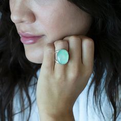 We are loving this oval chrysoprase ring, cradled in a loving embrace of a double-shank silver band. The genuine chrysoprase stone, with its calming shades of green, exudes serenity and elegance. As you slip this ring onto your finger, you'll feel a deep connection to the Earth's natural wonders, as the chrysoprase's ethereal hues seem to capture the essence of a lush forest glade or a tranquil emerald lake. Gemstone - Genuine Chrysoprase 950 Sterling silver High polish finish Approx. 0.8" L x 0 Oval Chrysoprase Opal Ring For Gift, Green Oval Moonstone Gemstone Ring, Oval Green Moonstone Gemstone Ring, Chrysoprase Emerald Ring With Oval Cabochon For Gift, Green Oval Moonstone Ring, Oval Green Onyx Rings, Oval Green Chalcedony Rings, Green Oval Chalcedony Rings, Forest Glade