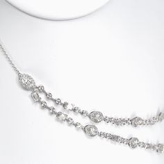 The Statement Opera Two Row Multi-Shape Halo Diamond Station Necklace is a breathtaking embodiment of luxury and elegance. This exquisite piece of jewelry is a true work of art, meticulously crafted to exude sophistication and charm. At the forefront of this necklace are two opulent rows adorned with an array of diamonds featuring various shapes. Each marquise diamond is encircled by a delicate halo, enhancing its brilliance and creating an ethereal glow. The combination of different diamond shapessuch as round brilliants, marquise and emerald cutsadds a captivating allure, capturing the eye with its symphony of shapes and sparkle. Luxury Diamond Cut Station Necklace For Formal Occasions, Luxury Brilliant Cut Diamond Station Necklace, Luxury White Gold Marquise Diamond Necklace, Luxury Elegant Marquise Necklace, Luxury Marquise Cut Diamond Necklace, Luxury Diamond Necklace With Jewels For Anniversary, Formal Diamond Necklace With Jewels, Silver Chain Necklace With Brilliant Cut, Formal Fine Jewelry Necklaces With Jewels