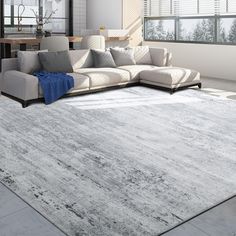 a living room with a large gray rug on the floor and a white couch in front of it