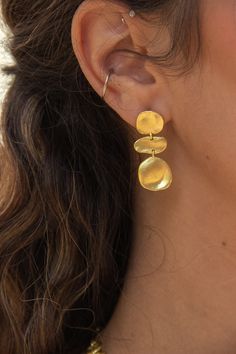 -18k gold plated earrings with molten brushed gold coins. -Measures 1" -Handmade in Brazil -18k gold plated over brass Unique Jewelry Gold, Gold Seventies Inspired Jewelry, Funky Jewelry Gold, Funky Gold Earrings, Cool Gold Earrings, Flamboyant Natural Jewelry, Handmade Gold Earrings, Gold Summer Jewelry, Textured Jewellery