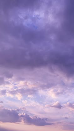 two people standing on the beach with their surfboards under a cloudy blue and purple sky