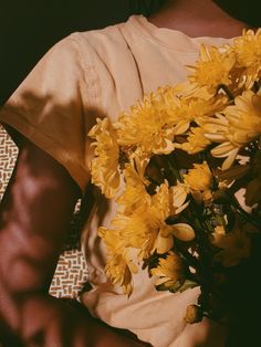 a woman holding a bouquet of yellow flowers