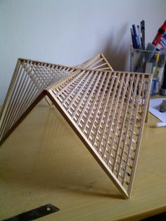 a wooden table topped with a metal object on top of it's side next to pens and pencils