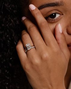 a close up of a person wearing a ring and holding her hand to her face