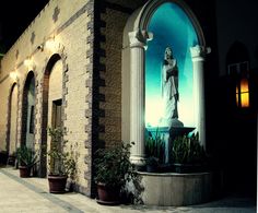 an image of a statue on the side of a building with potted plants in front