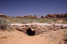 there is a large pipe in the middle of this dirt area that looks like it has been dug into some rocks