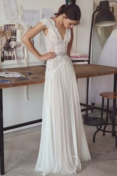 a woman standing in front of a table wearing a white dress with lace on it