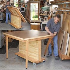 a man standing next to a wooden table in a room filled with woodworking supplies