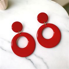 Stylish Red Dangle Hoops with a Modern Twist. Red hoop earrings in a retro style are always in vogue, having remained popular across several decades, from the 50's, 60's, 70's, 80's, and beyond. Available in in pierced or clip-on. Handmade with care, these earrings are not only trendy but also enjoyable and fun to wear. Treat yourself or surprise a friend with a gift of these vibrant, medium-sized hoops made from polymer clay and coated with resin on both sides. Featuring an open circular red ho Trendy Red Plastic Earrings, Red Round Resin Jewelry, Cheap Red Resin Earrings, Trendy Red Resin Earrings, Red Retro Round Earrings, Red Hoop Earrings, 80s Earrings, Resin Jewelry Diy, Dangle Hoop Earrings