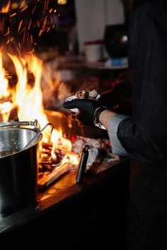 a person is cooking food over an open fire