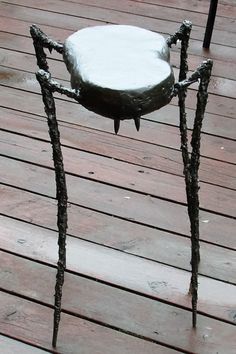 a snow covered chair sitting on top of a wooden floor next to a metal pole