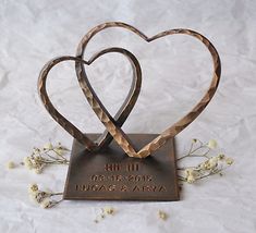 two heart shaped metal pieces on top of a plaque