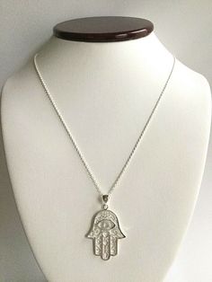 "925 STERLING SILVER HAMSA NECKLACE . FOR PROTECTION AND GOOD LUCK. 16\" TO 18\" ADJUSTABLE CHAIN PENDANT SIZE : 30 mm X 23 mm CADENA DE 925 PLATA ESTERLINA MANO DE FATIMA . LA MANO DE FATIMA PARA BUENA SUERTE Y PROTECCION. 16\" A 18\" AJUSTABLE CADENA TAMAÑO DEL DIJE :30 mm X 23 mm" Symbolic Silver Necklace With Sterling Clasp, Traditional Silver Charm Necklaces As Gift, Sterling Silver Spiritual Necklace, Spiritual Sterling Silver Charm Necklaces In Silver, Spiritual Sterling Silver Charm Necklace In Silver, Symbolic Sterling Silver Necklace Stamped 925, Sterling Silver Round Pendant Charm Necklace For Good Luck, Symbolic Sterling Silver Jewelry With Lobster Clasp, Sterling Silver Charm Necklace For Good Luck