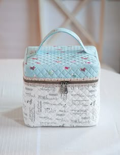 a blue and white quilted box sitting on top of a table next to a chair