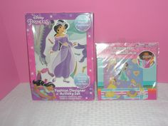 two disney princess paper dolls next to each other on a pink tableclothed surface