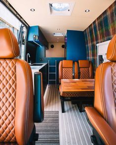 the interior of an rv with leather seats and wood table in front of sink area