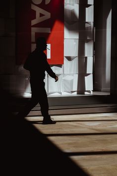 the shadow of a man holding a tennis racquet in front of a building