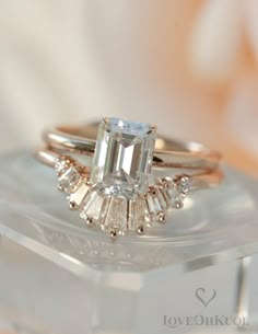 an emerald cut diamond ring on top of a clear box