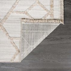 an area rug with white and beige colors on top of a wood flooring surface