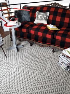 a red and black checkered couch sitting on top of a floor next to a table