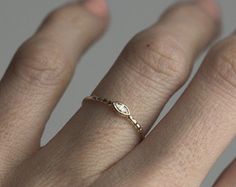 a woman's hand with a gold ring on her left hand and a diamond in the middle