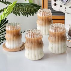 three vases sitting on top of a table next to a toaster and coffee pot