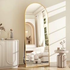 a mirror sitting on top of a wooden floor next to a white couch and table