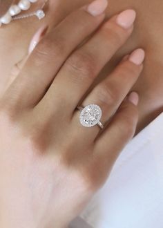 a woman's hand with a diamond ring on her left side and pearls around the middle