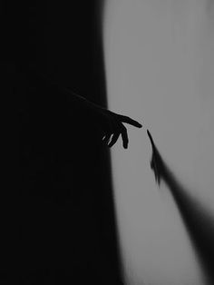 a person's hand reaching out from behind a wall with the shadow of their arm