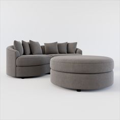 a large gray couch sitting on top of a white floor next to a round ottoman