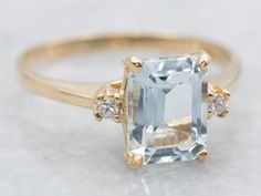 an aquamarinee and diamond ring on a white surface