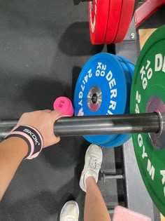 a person holding a barbell in their hand while standing next to a weight machine