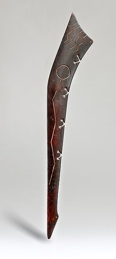 a metal object with writing on it sitting on top of a wooden stand in front of a gray background