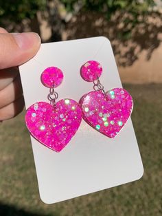 "Each pair of neon sparkly pink heart earrings are handmade to order, therefore no two pairs are identical! Every resin jewelry piece in my shop is slightly unique and one of a kind! However, I try to get as close to the photos as possible :) Made with non-toxic stainless steel stud earrings. Nickel-free & hypoallergenic.  Hearts are approximately 1.25\", and are made with epoxy resin and neon hot pink iridescent glitter ✨  These dangle drop heart earrings are perfect for Valentine's Day, everyd Girly Earrings, Iridescent Resin, Jewelry Kawaii, Pink Heart Earrings, Kawaii Items, Diy Earrings Polymer Clay, Resin Accessories, Pink Iridescent, Earrings Handmade Dangle