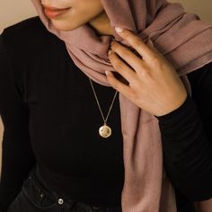 a woman wearing a hijab and a necklace with a medallion on the front